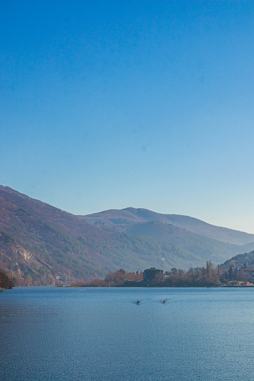 body of water near mountain under blue sky during daytime