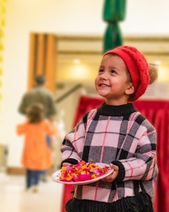girl in red and white plaid dress shirt and green knit cap holding red and white