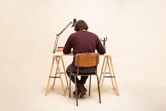 Portrait of Ramón Páez sitting at a desk with books and a typewriter in a minimalist room.