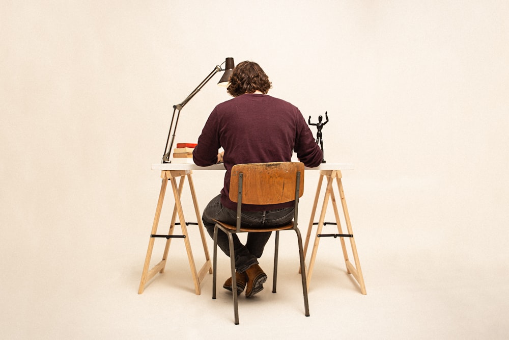 man in brown shirt sitting on brown wooden chair