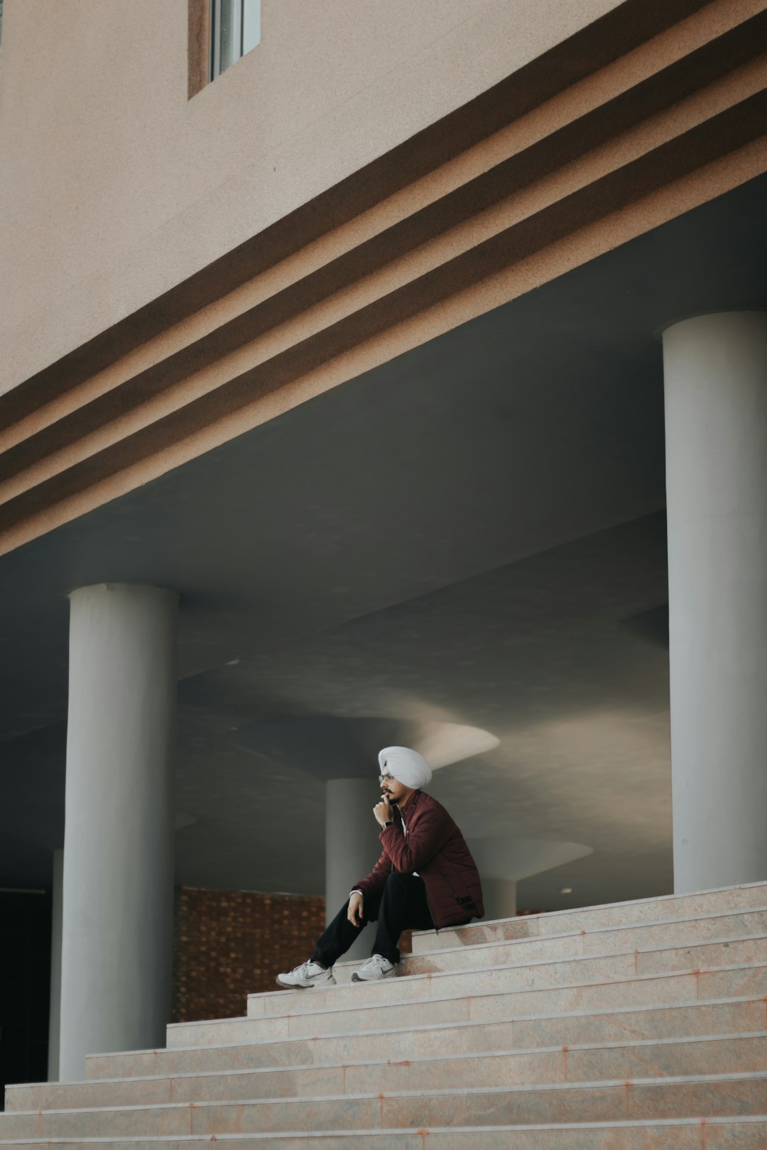 woman in black jacket and white knit cap standing on brown concrete stairs