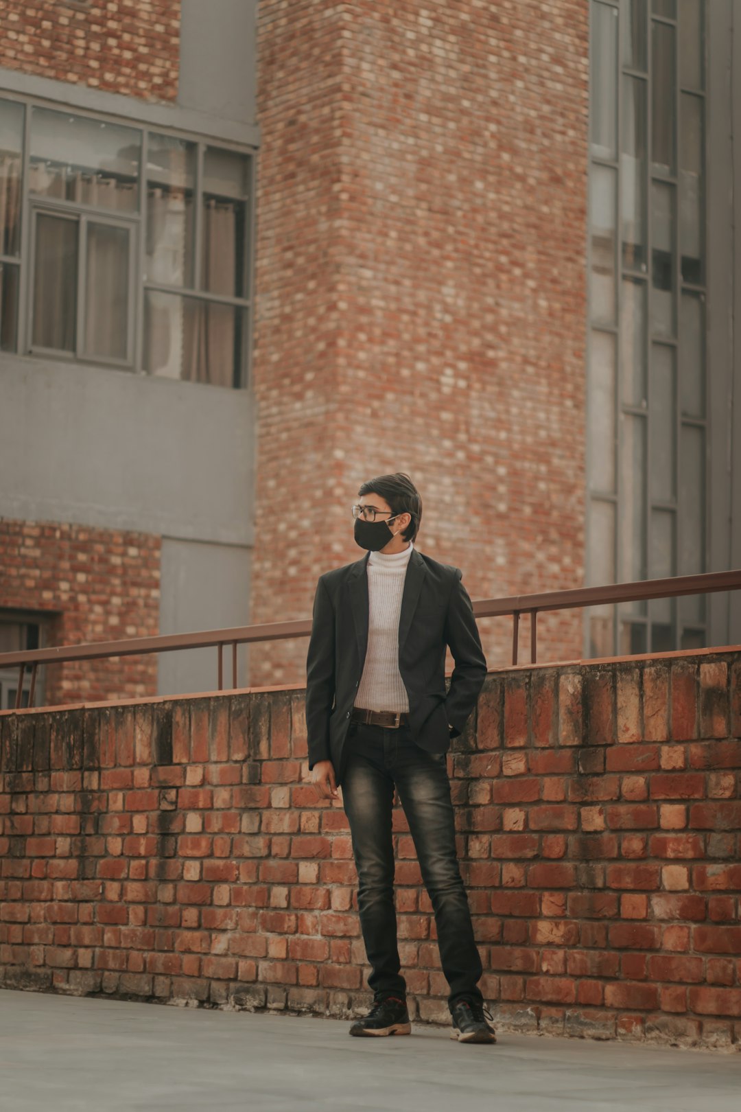 man in black jacket and black pants standing on brown concrete stairs