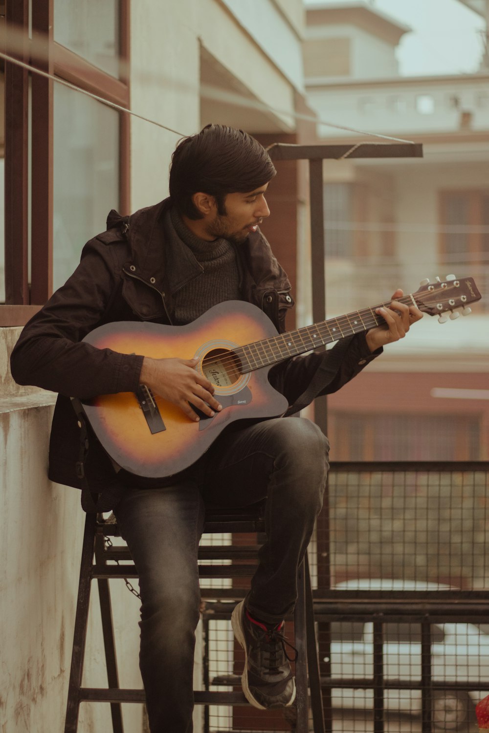 man in black jacket playing guitar