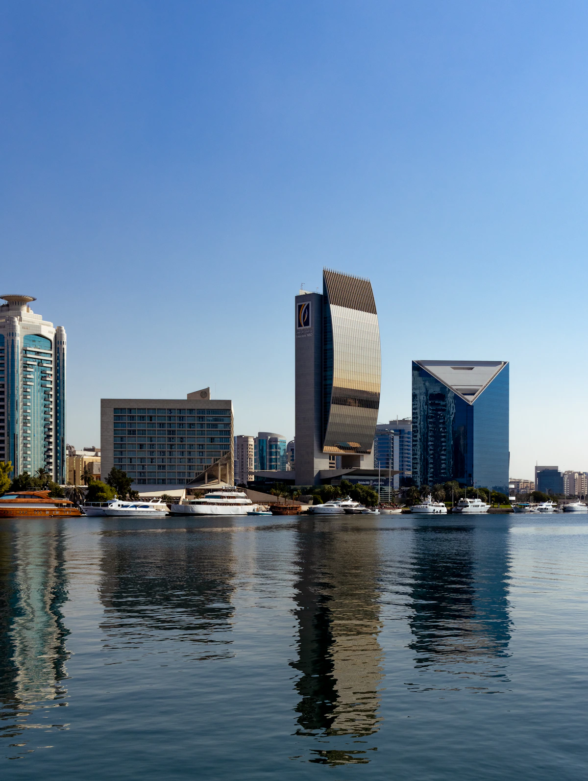 An abra boat crossing Dubai Creek with the city reflected in the water
