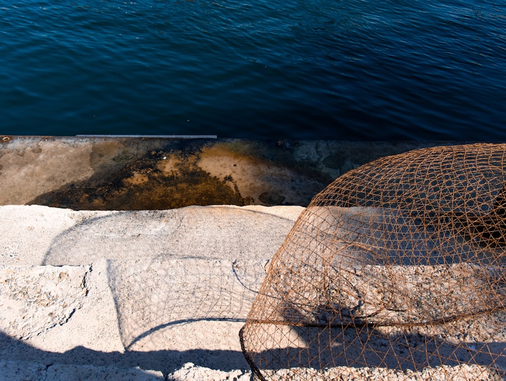 brown net on white sand near body of water during daytime
