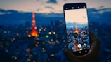 A traveler holding a smartphone with simnow eSIM activated, overlooking a vibrant city skyline at dusk.