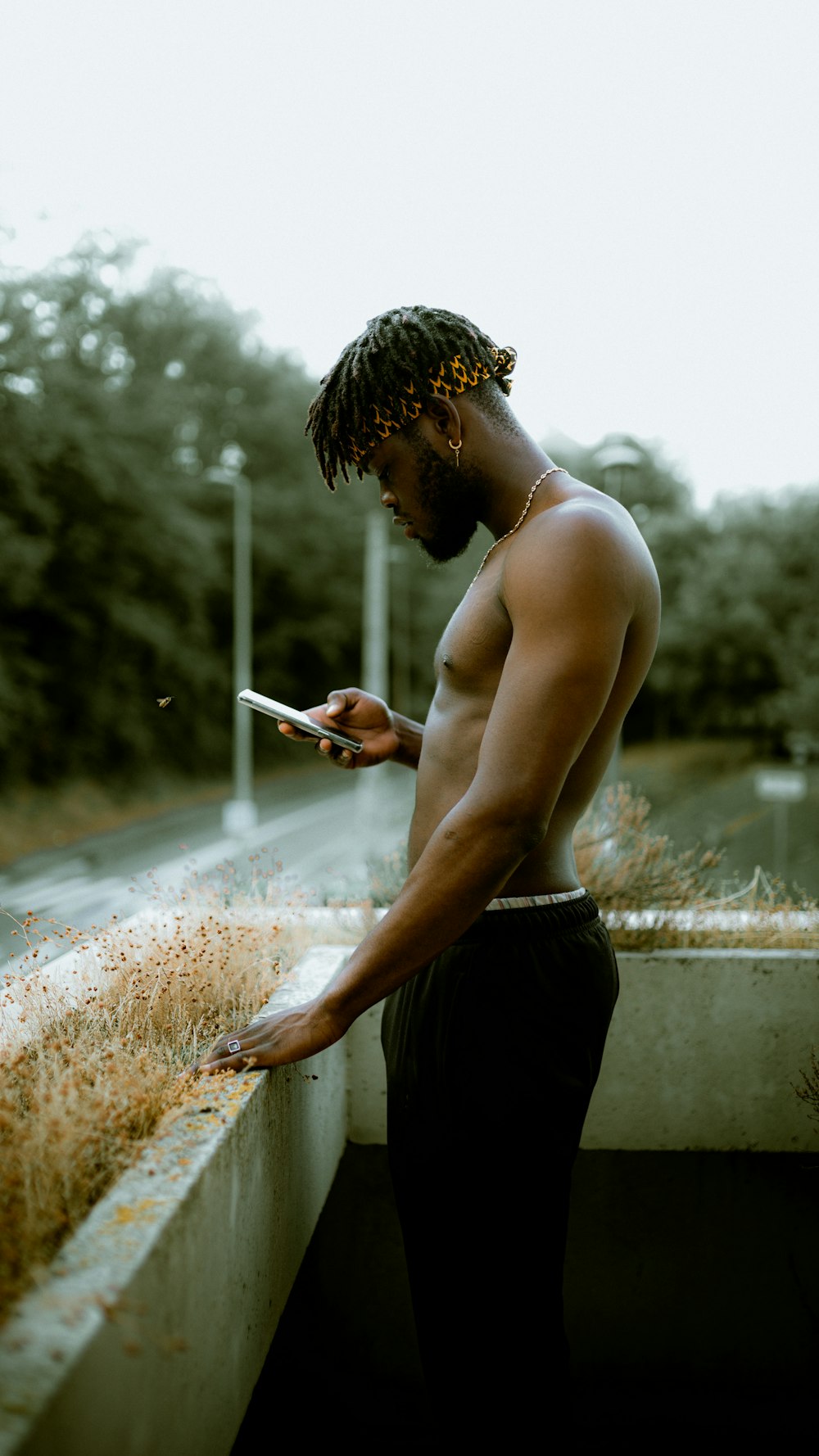 topless man in black shorts holding smartphone