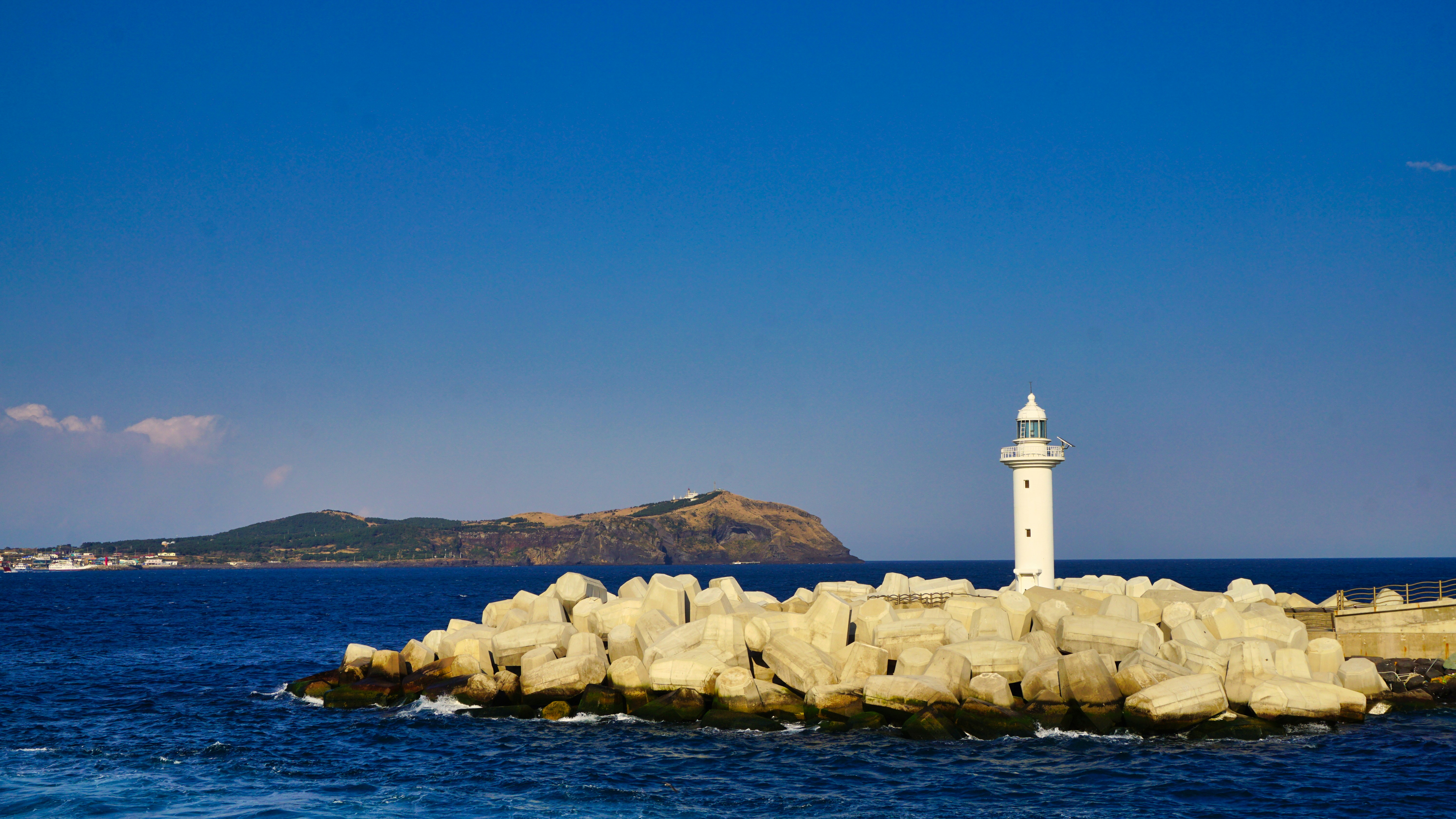 white lighthouse on rocky shore during daytime, 2019.03.15 Udo, Korea