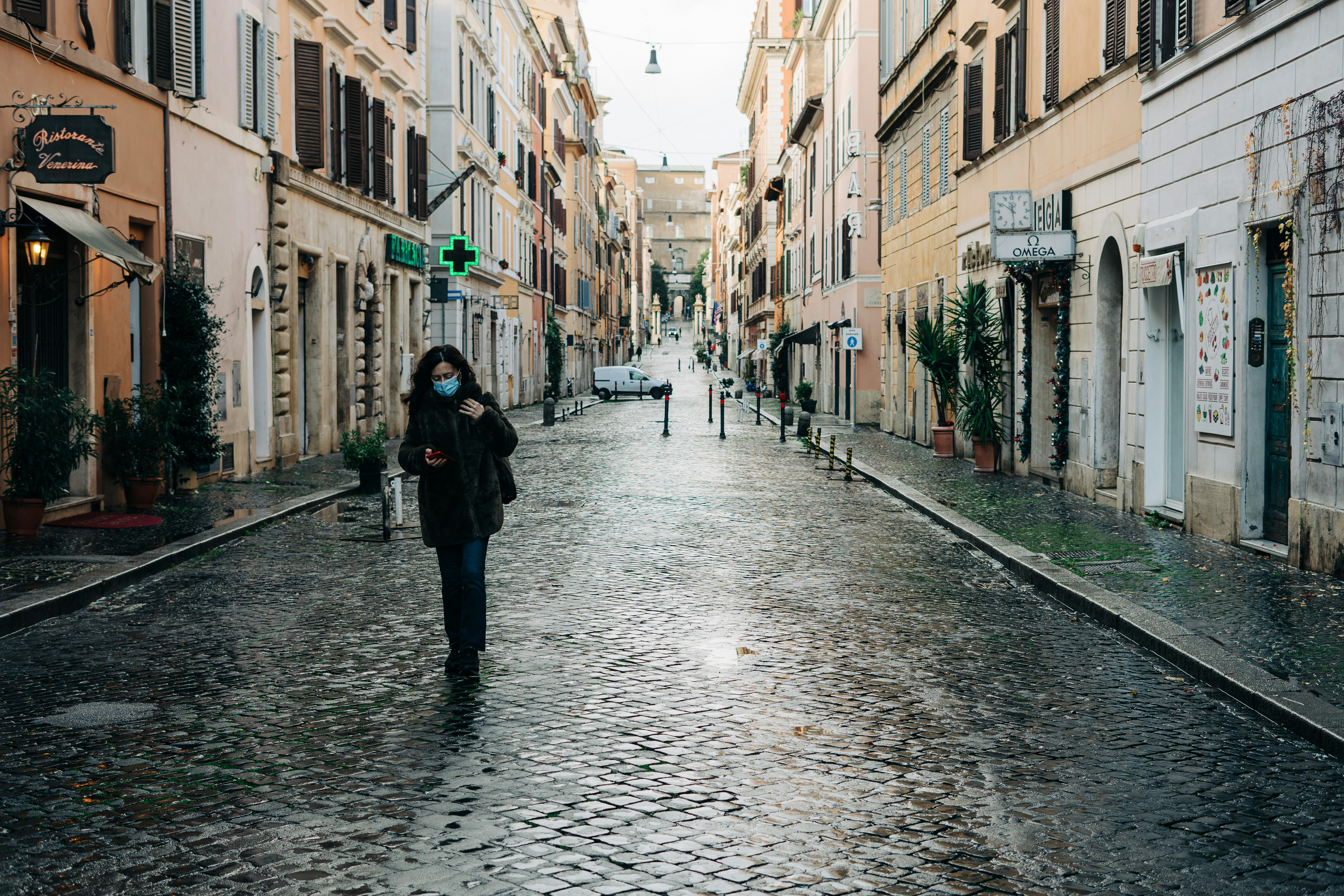 A lone woman in a face mask strolls down an unusually empty street leading up to the Vatican gates during the Covid-19 lockdown in Rome, Italy
