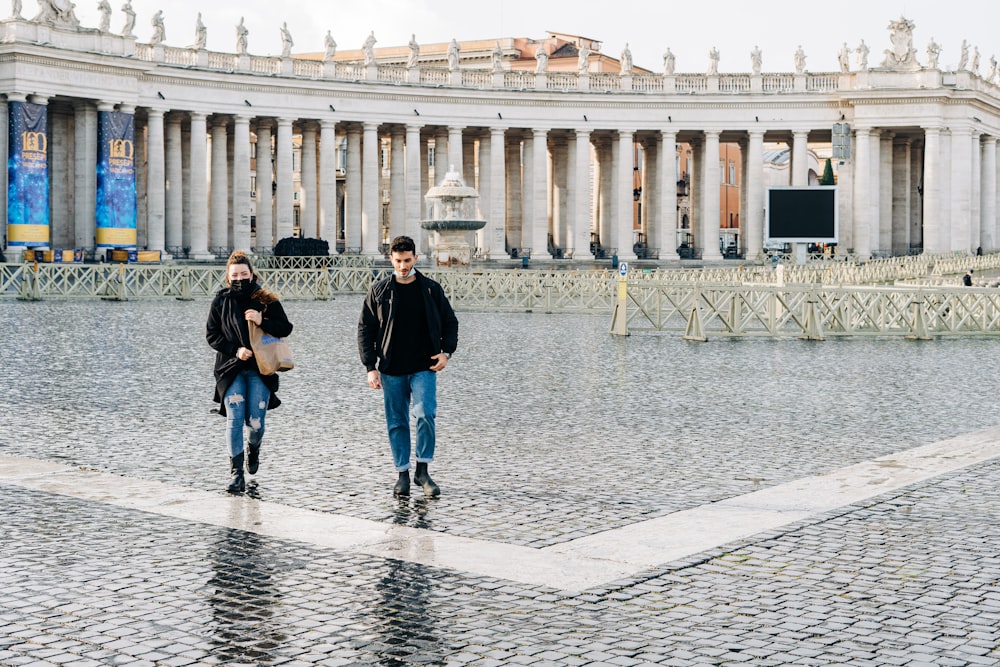 man and woman walking on gray concrete pavement during daytime