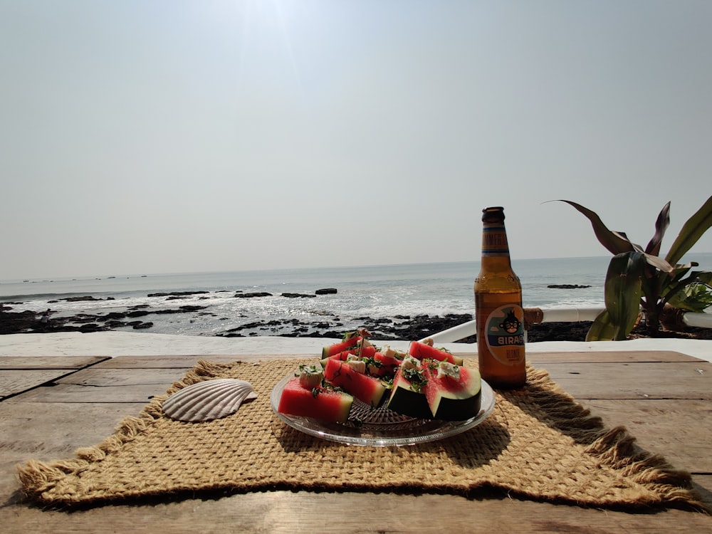 brown glass bottle on brown woven mat on beach during daytime