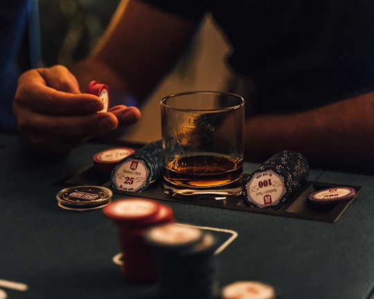 Hands holding chips over a green felt betting table under warm lighting