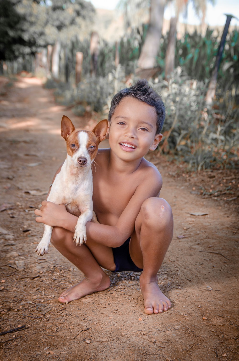 topless woman sitting on ground with brown and white short coated dog
