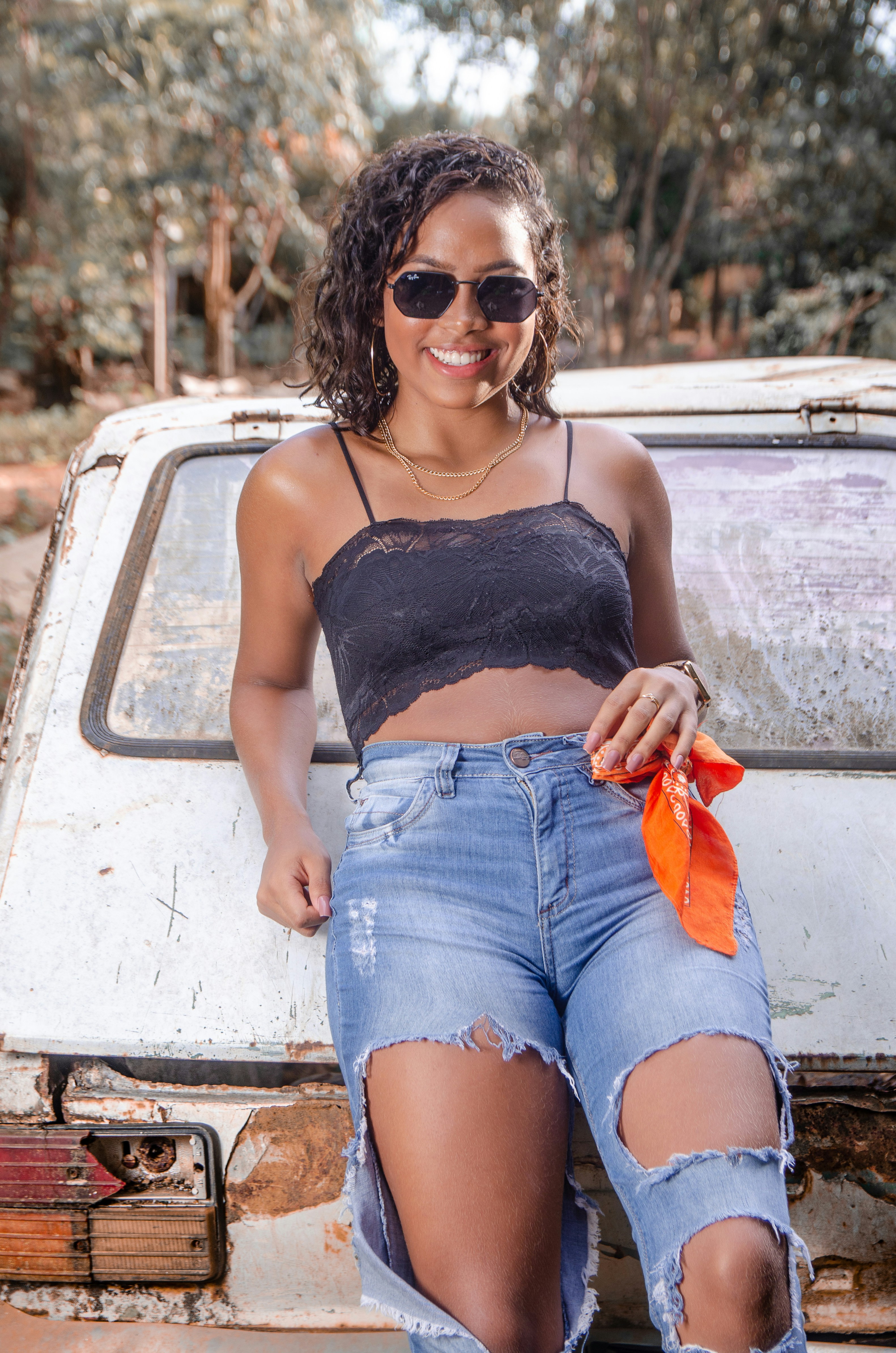 woman in black spaghetti strap top and blue denim shorts sitting on white car