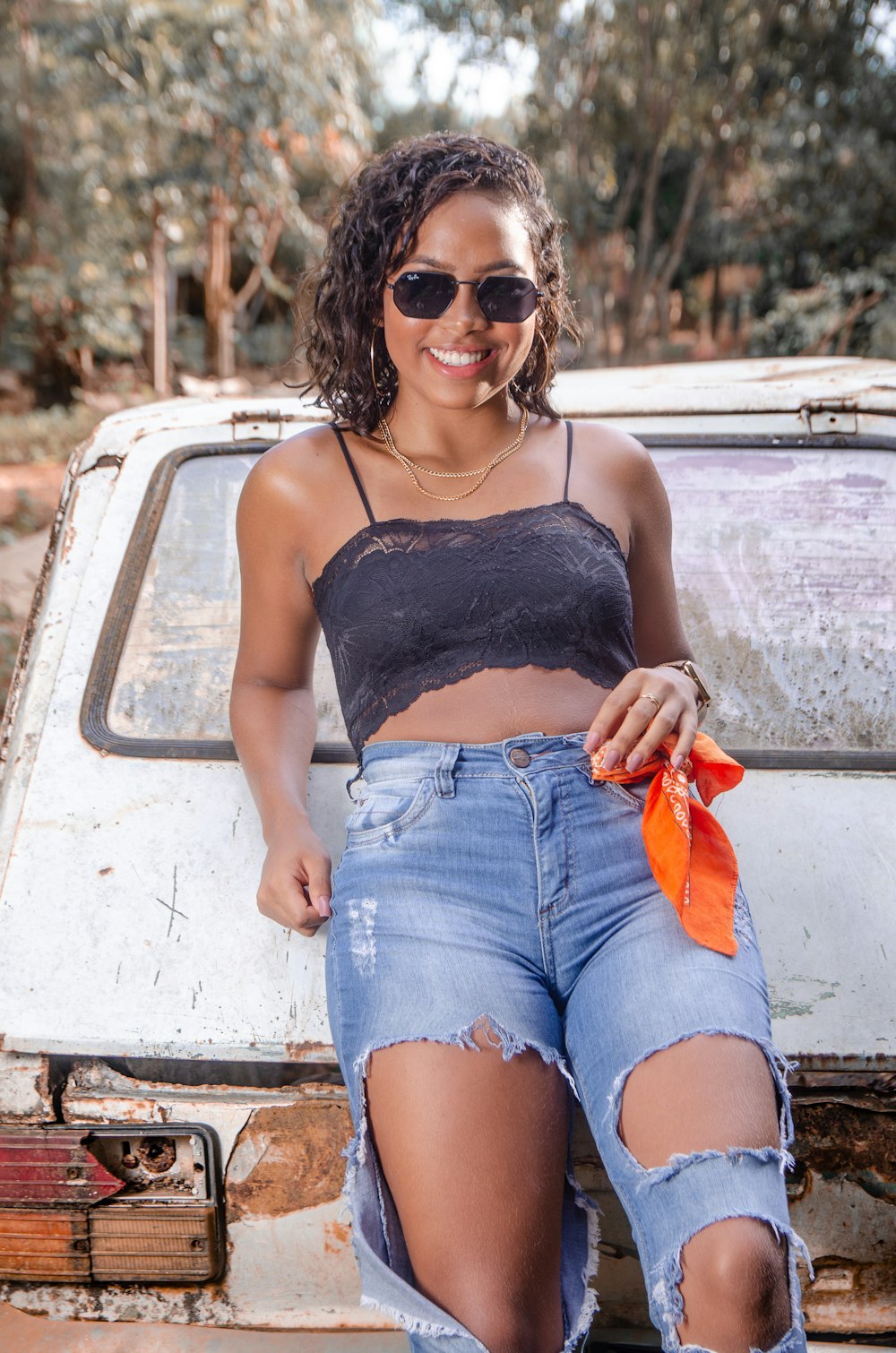 woman in black spaghetti strap top and blue denim shorts sitting on white car