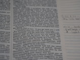 A page from a book with text in printed columns, discussing a biblical passage. There are handwritten notes on the right side in pen, adding personal annotations to the printed material.