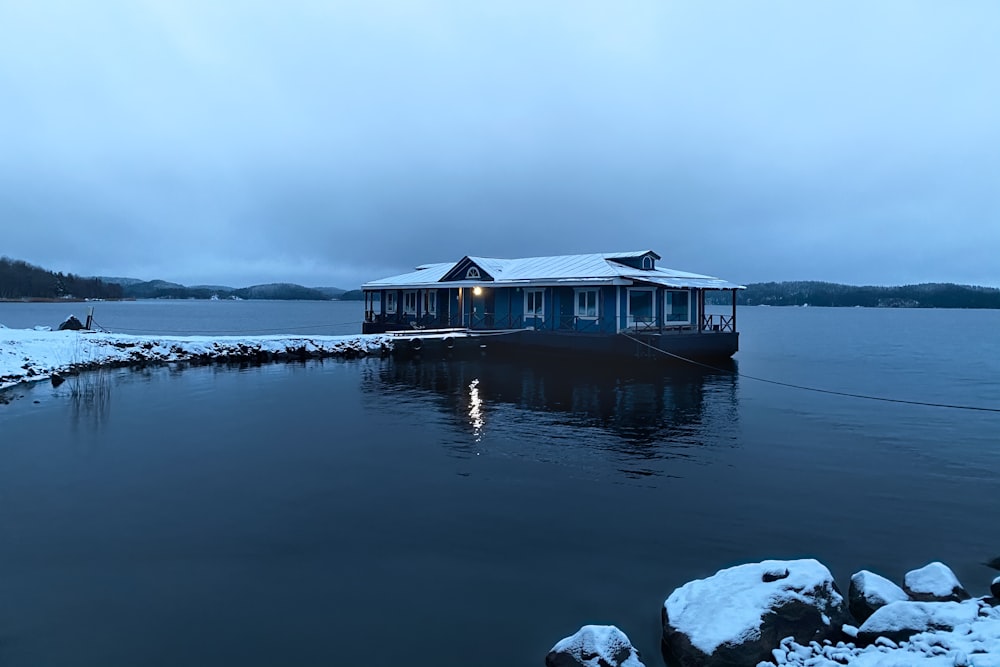 brown wooden house on snow covered ground near body of water during daytime