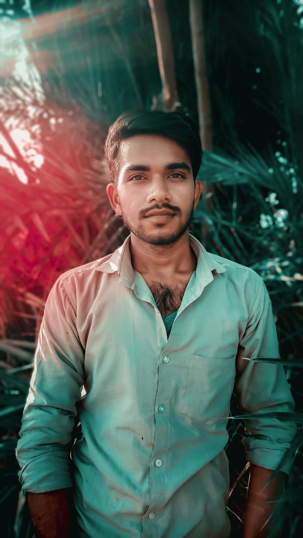 man in brown button up shirt standing near green plants