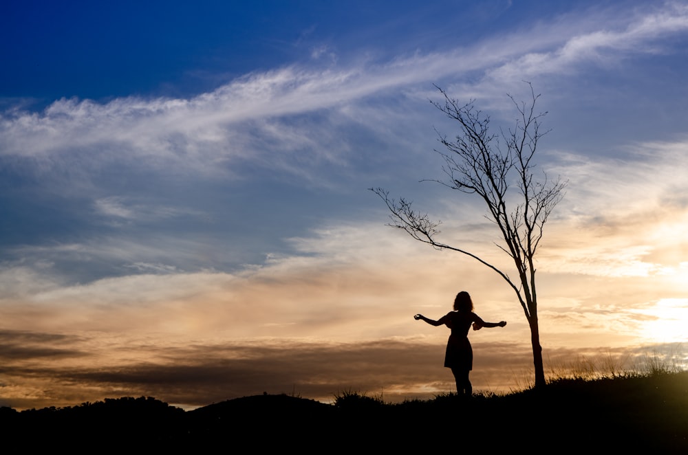 silhouette of man jumping on hill during sunset