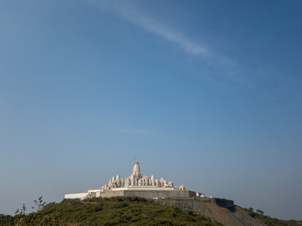 white concrete building on top of hill under blue sky during daytime