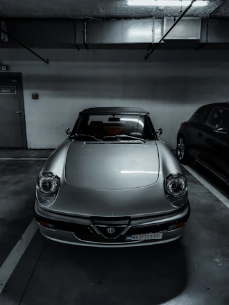 A pristine vintage sports car parked inside a spotless, well-lit storage facility.