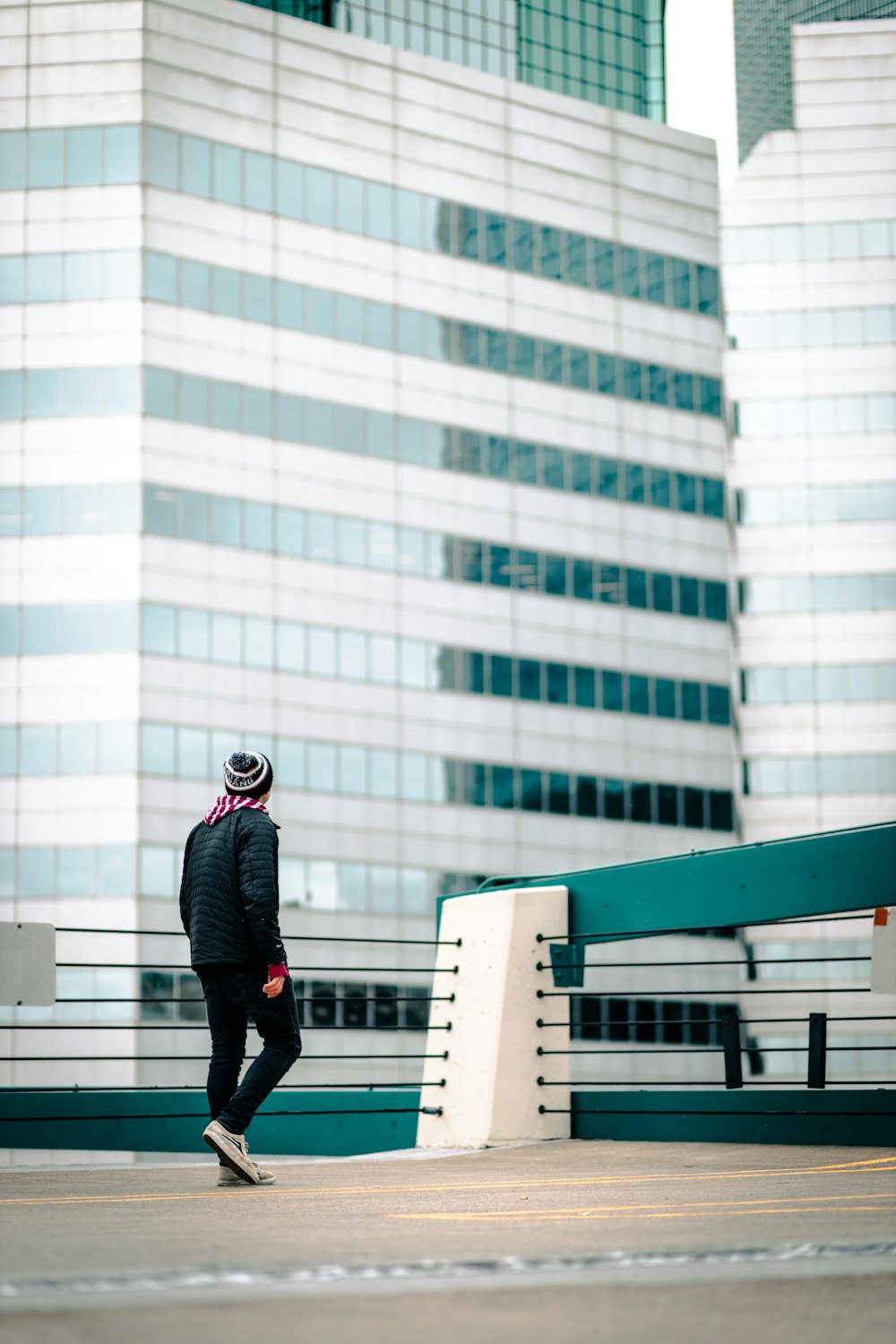 昼間、白いコンクリートの建物の上に立つ黒いジャケットとズボンの男
