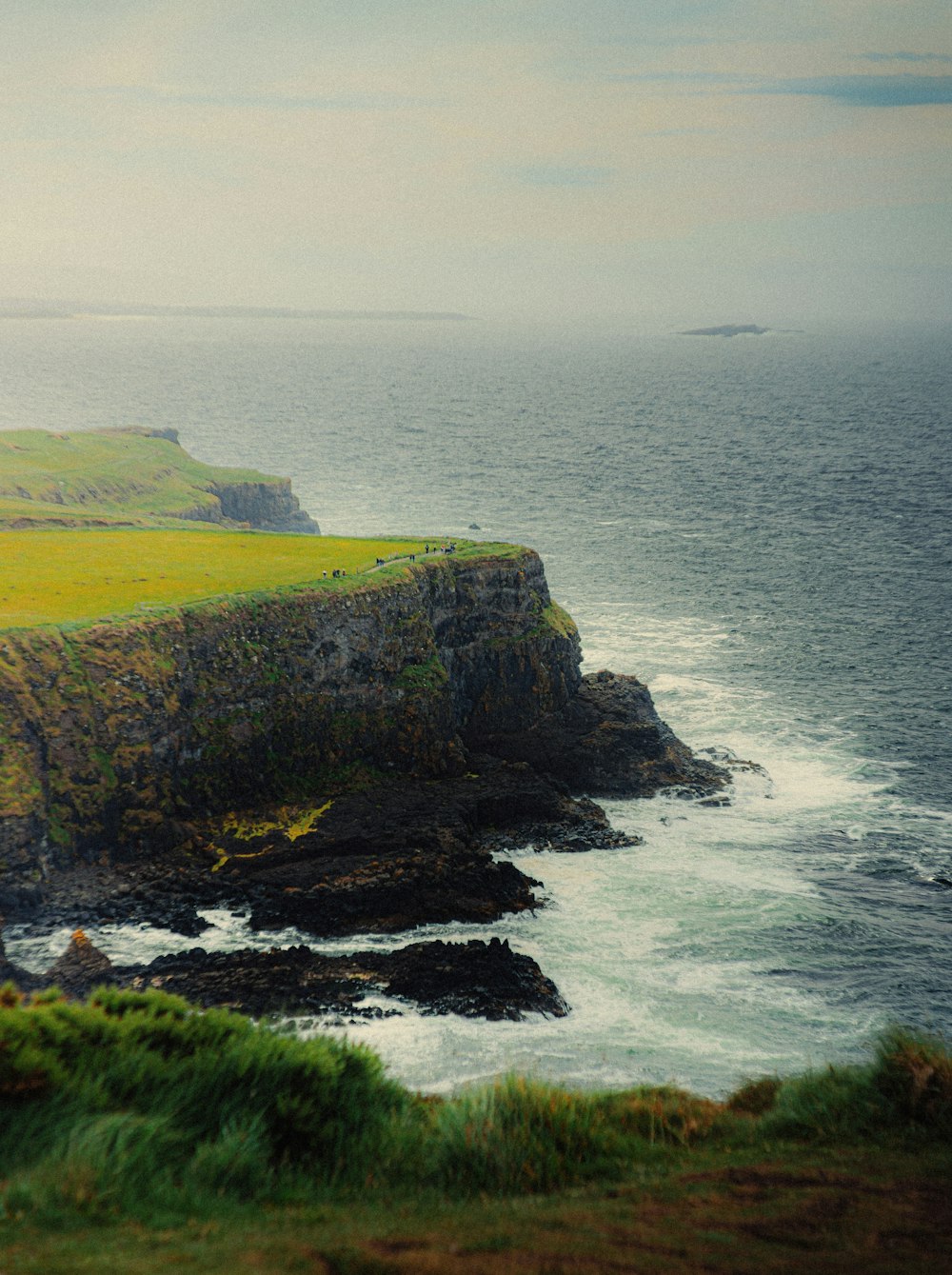 green grass covered mountain beside sea during daytime