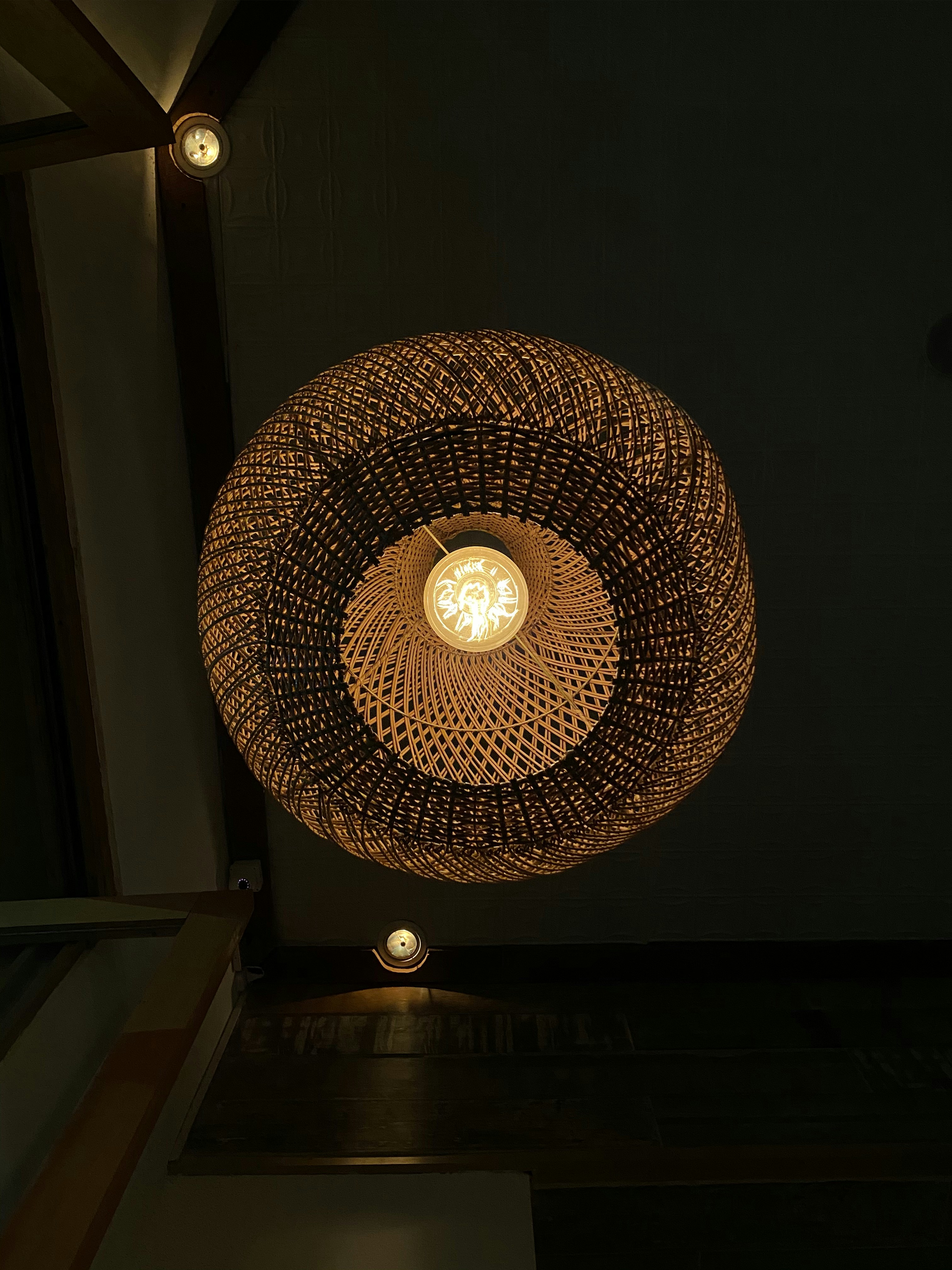 Large hand-woven rattan globe pendant lamp with warm Edison bulb in a cozy bedroom