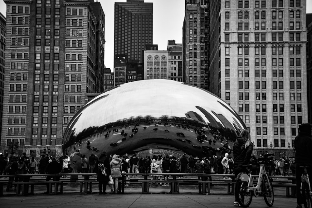 grayscale photo of people walking on street near cloud gate