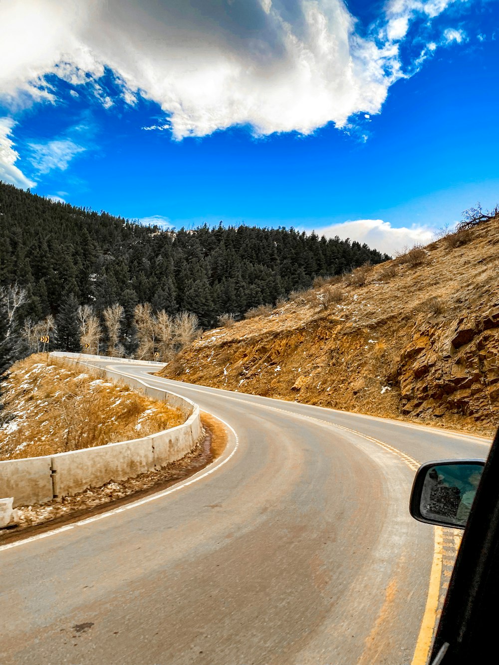 gray asphalt road between green trees under blue sky during daytime