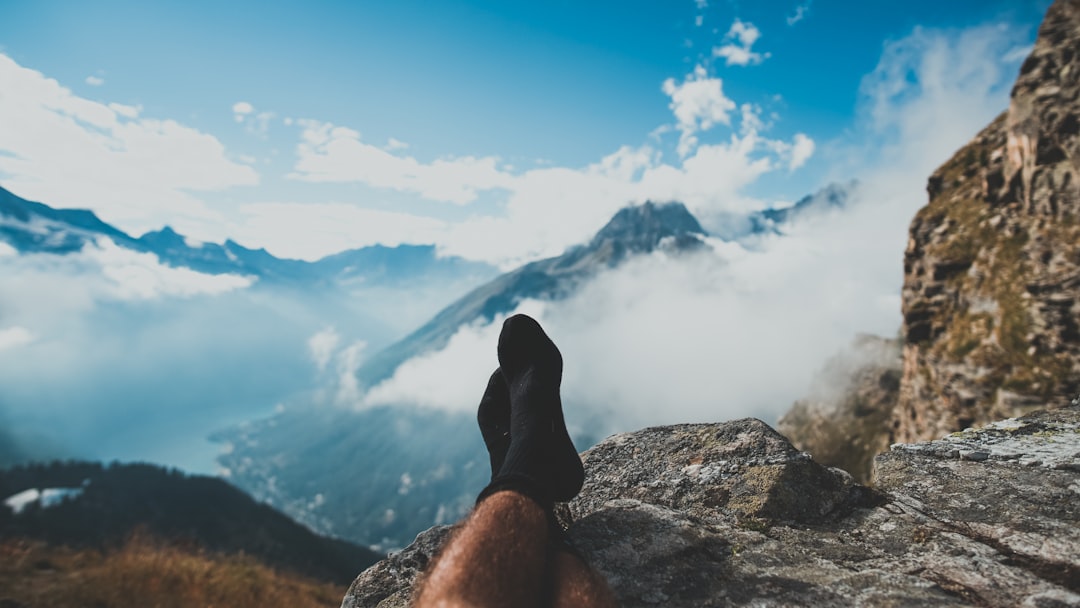 person in black sock sitting on rock formation during daytime, I