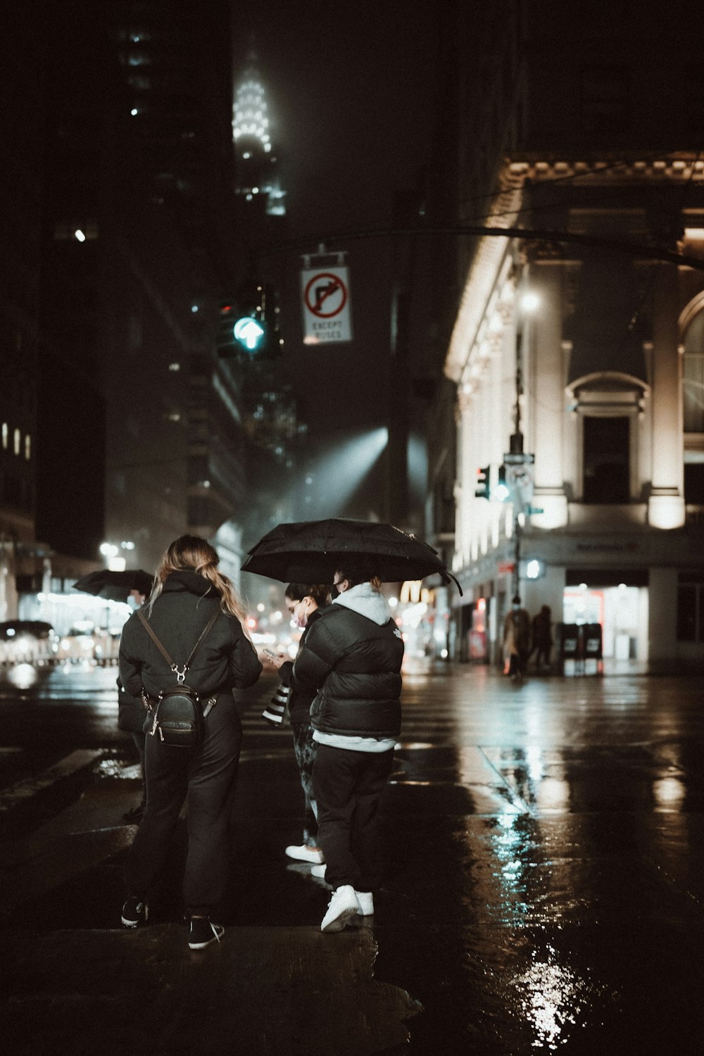 man in black jacket holding umbrella walking on street during night time