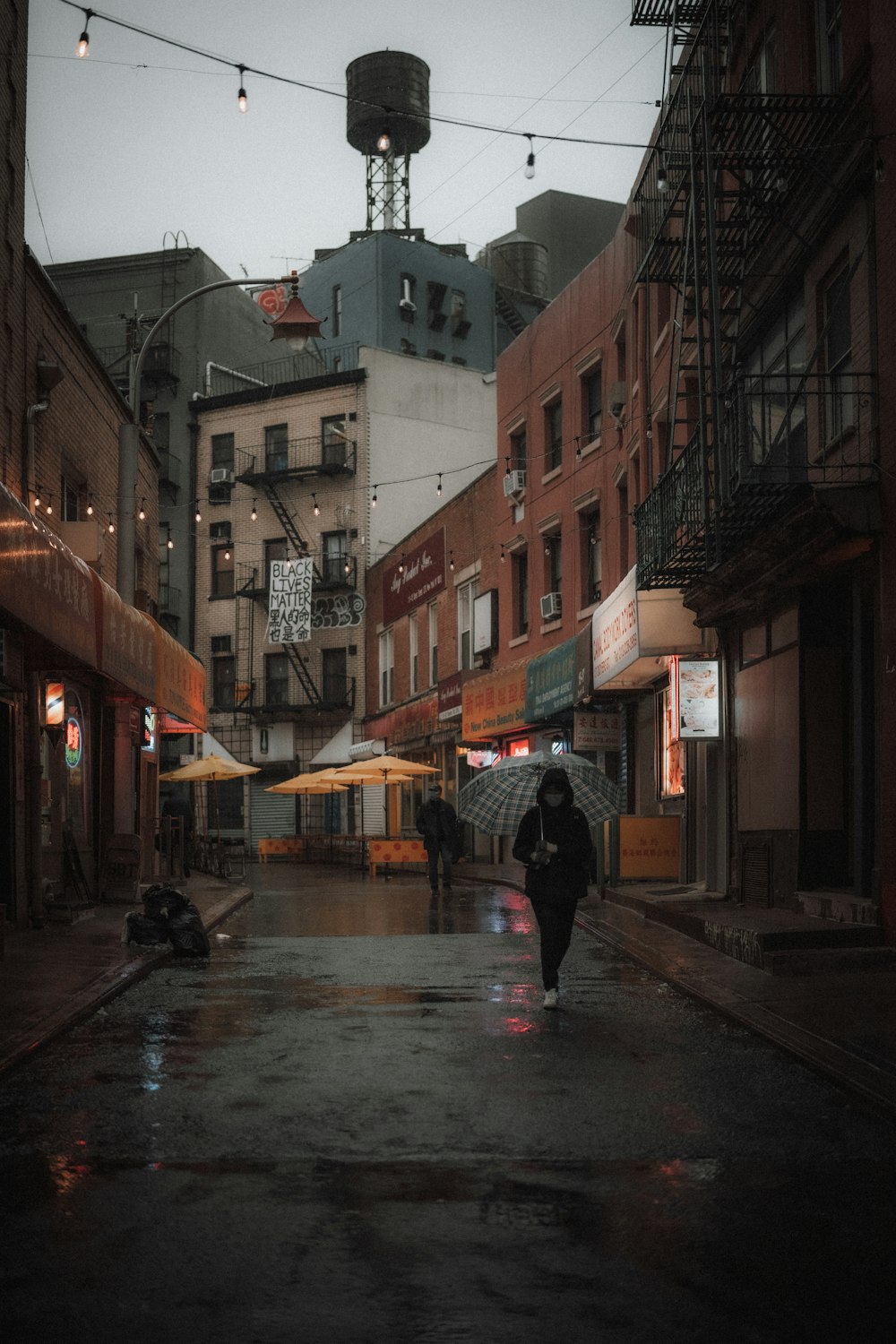 person in black jacket holding umbrella walking on street during daytime