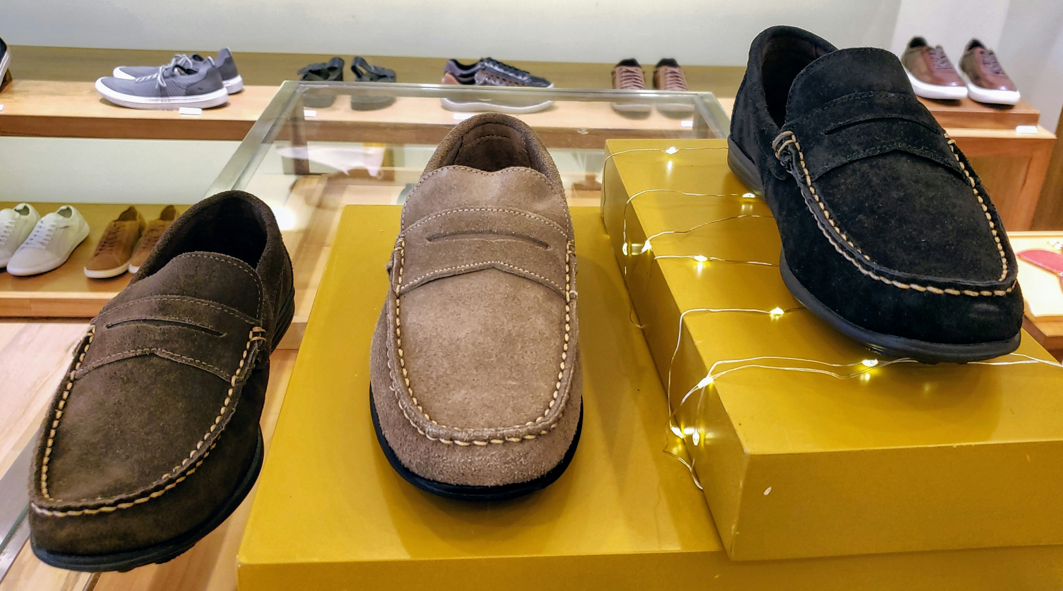 Elegant suede loafers on dark surface, soft ambient lighting