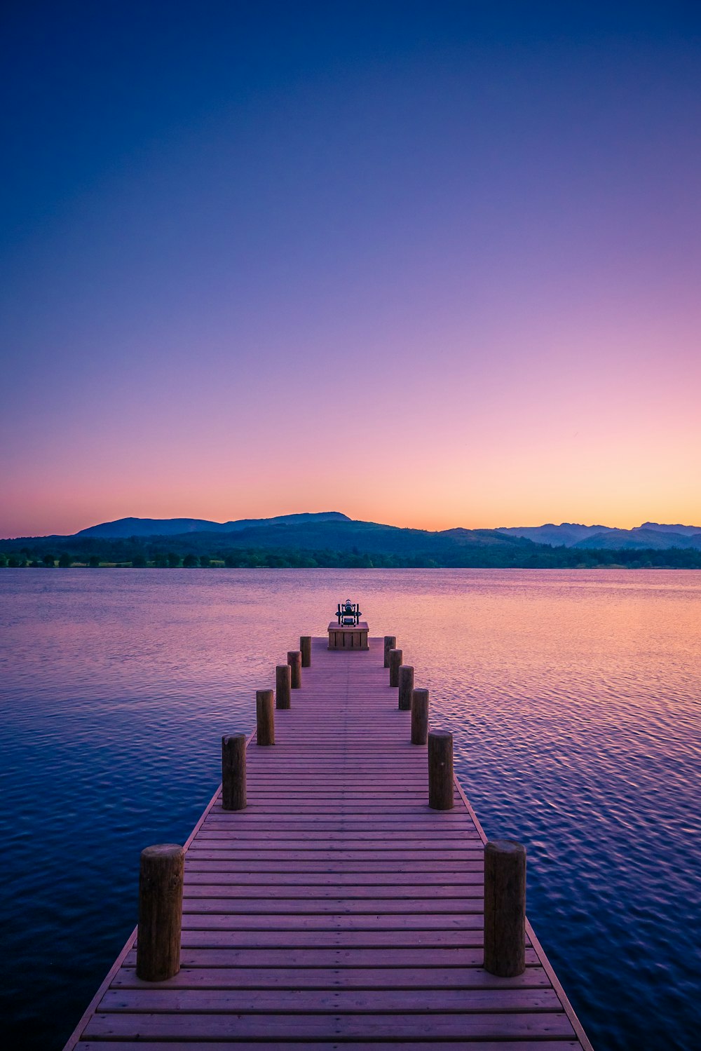 muelle de madera marrón en cuerpo de agua durante la puesta de sol