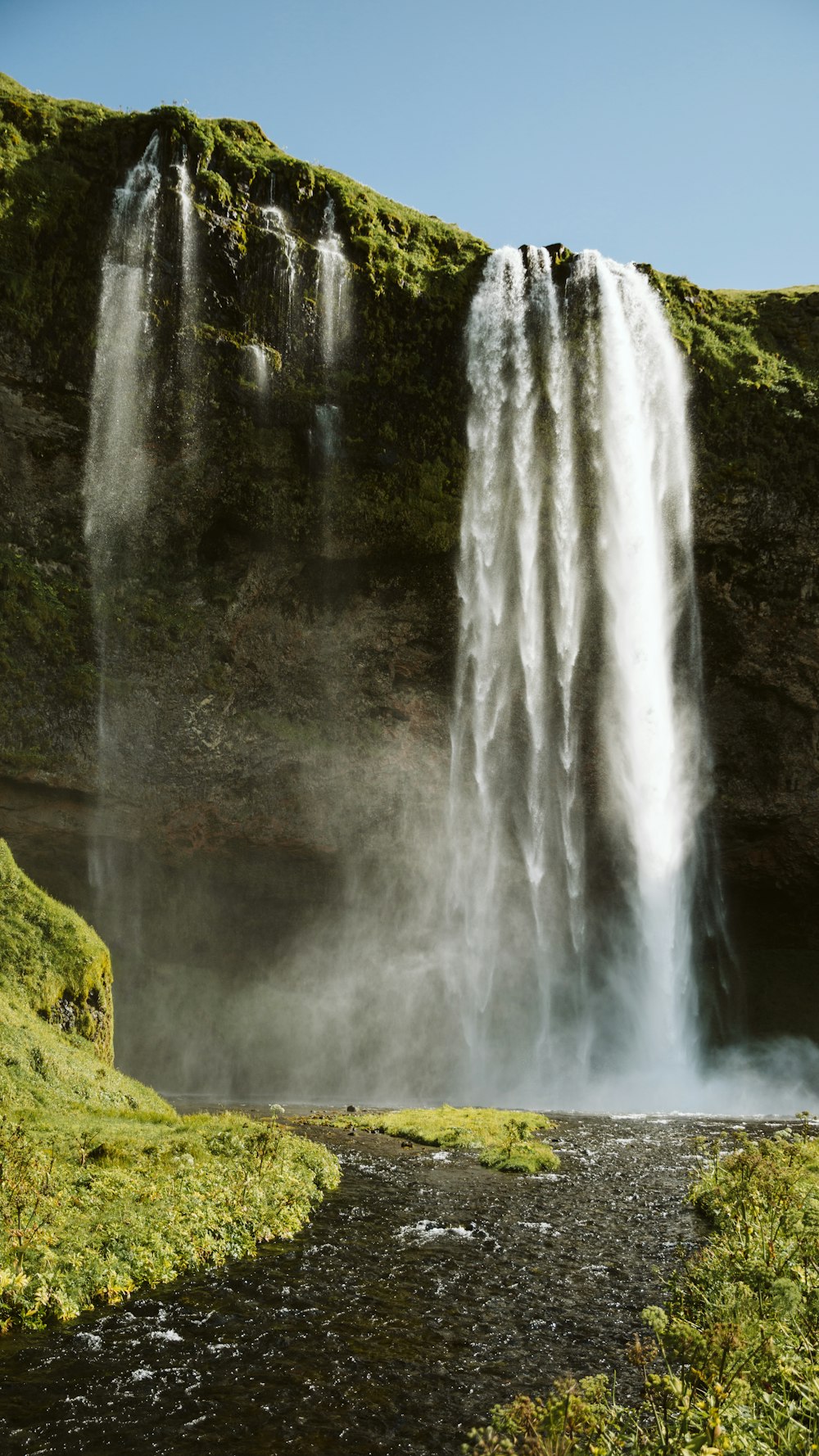 waterfalls on green grass field during daytime