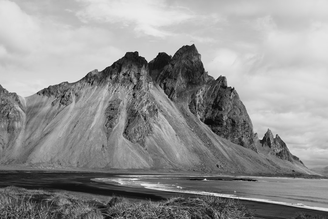 grayscale photo of mountain under cloudy sky