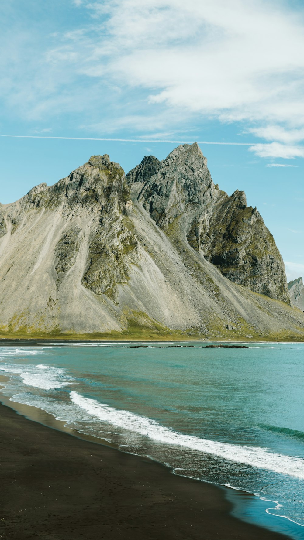 Montaña rocosa gris al lado del cuerpo de agua durante el día