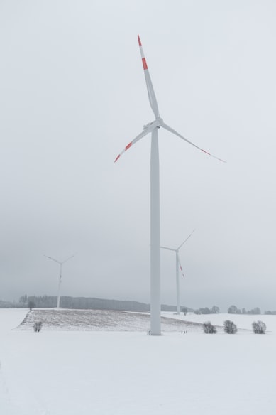 white wind turbine on snow covered ground during daytime