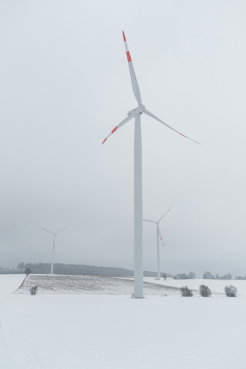 weiße Windkraftanlage tagsüber auf schneebedecktem Boden