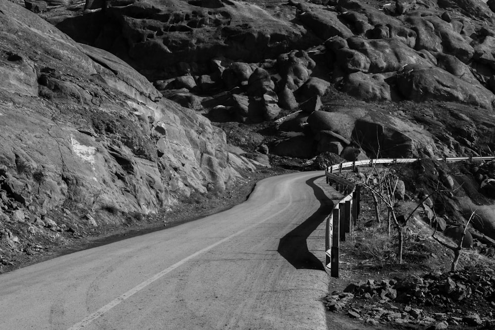 grayscale photo of road between rocky mountains