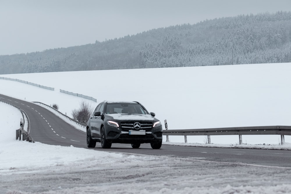 sedán negro en carretera cubierta de nieve durante el día