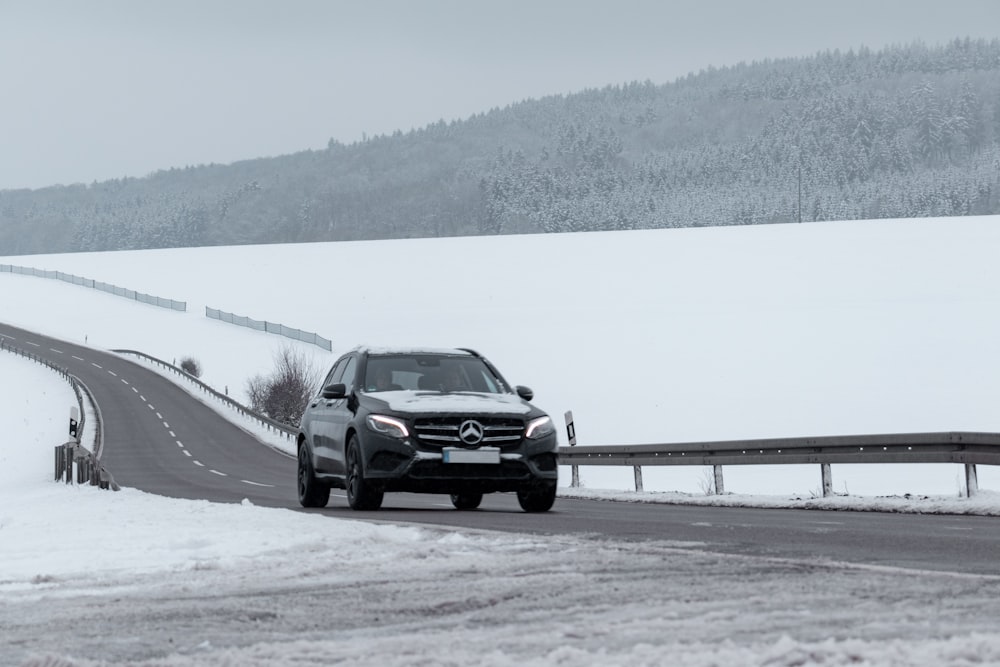 black sedan on snow covered road during daytime