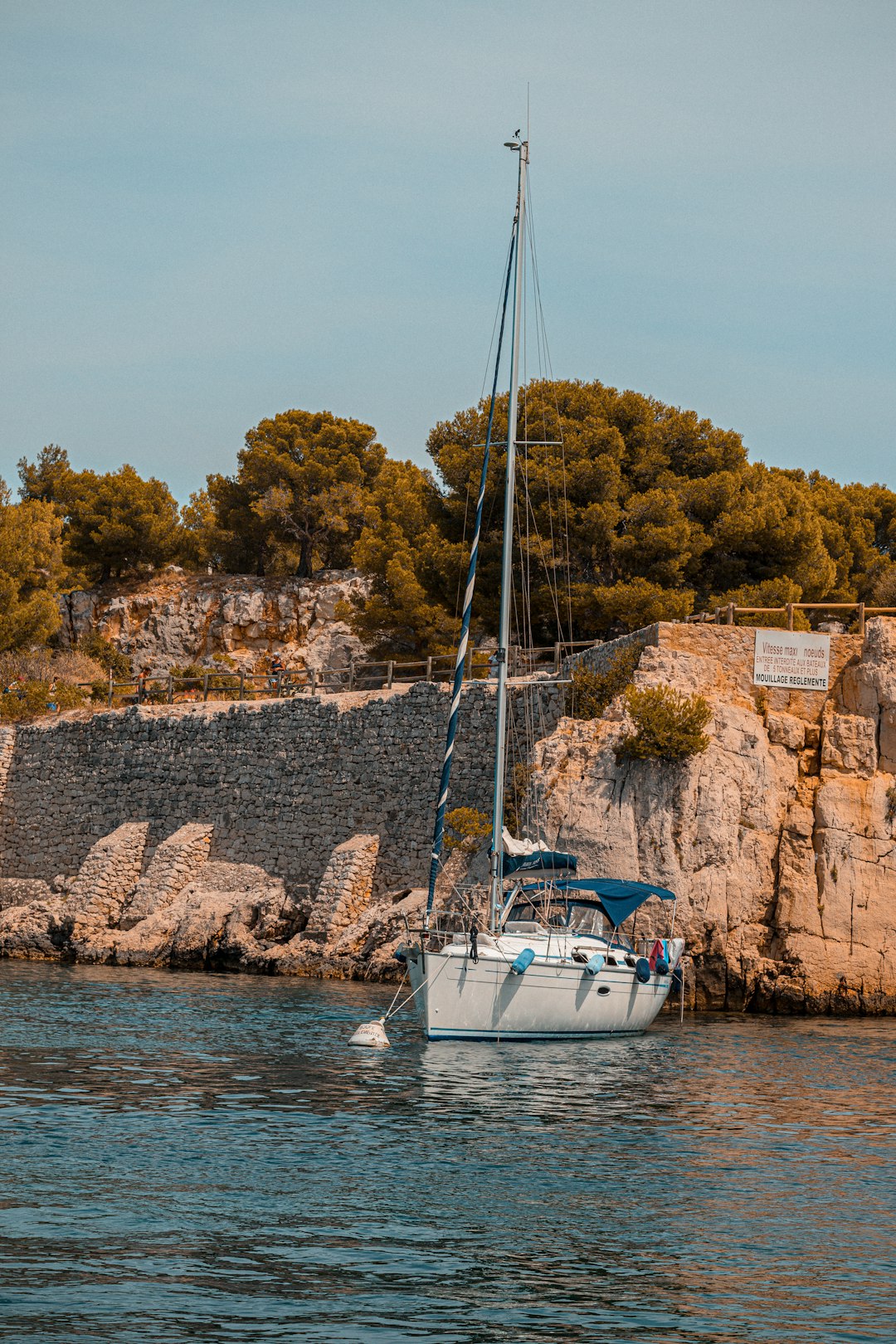 white and blue boat on sea near brown rock formation during daytime