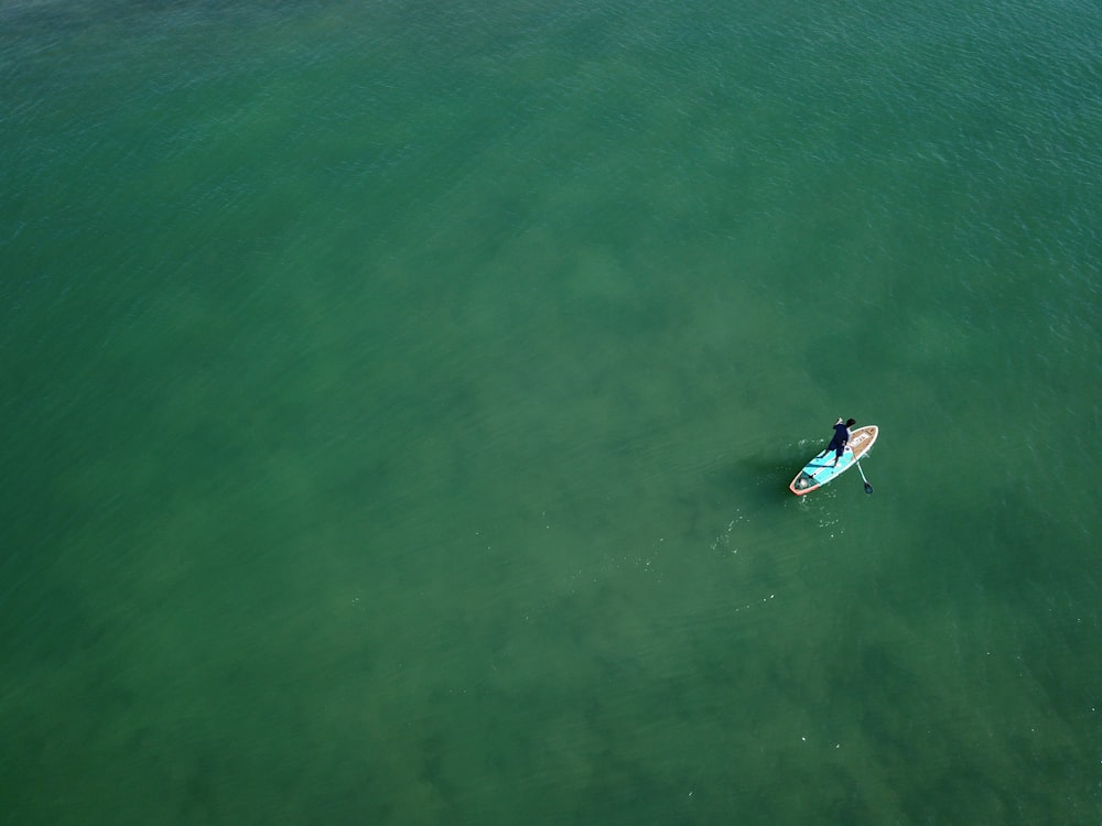 Persona che fa surf sul mare verde durante il giorno