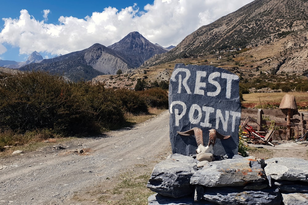 person sitting on rock near mountain under blue sky during daytime