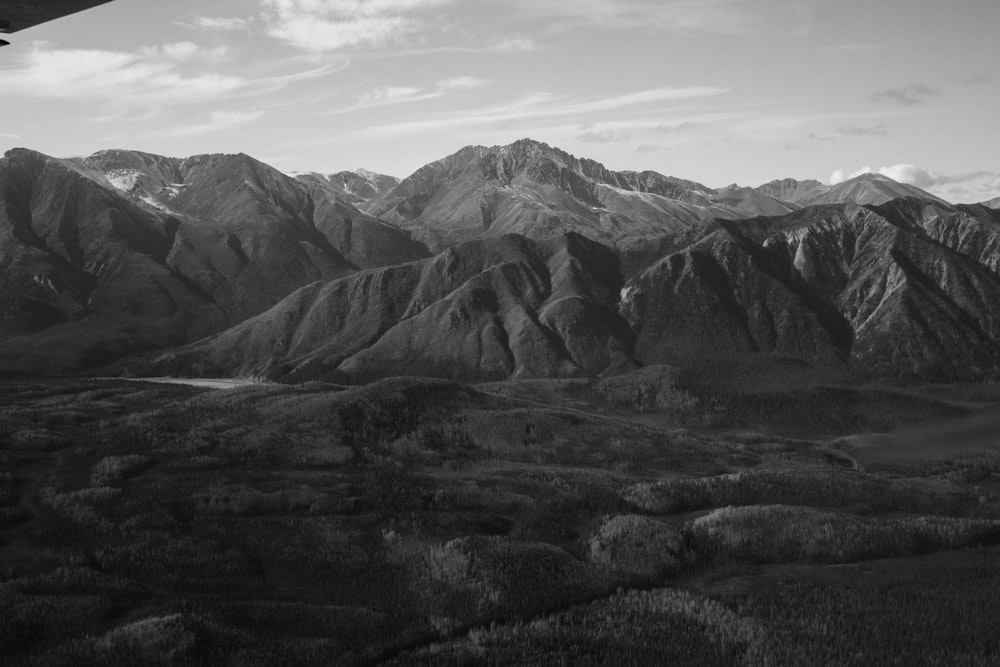 grayscale photo of mountains under cloudy sky