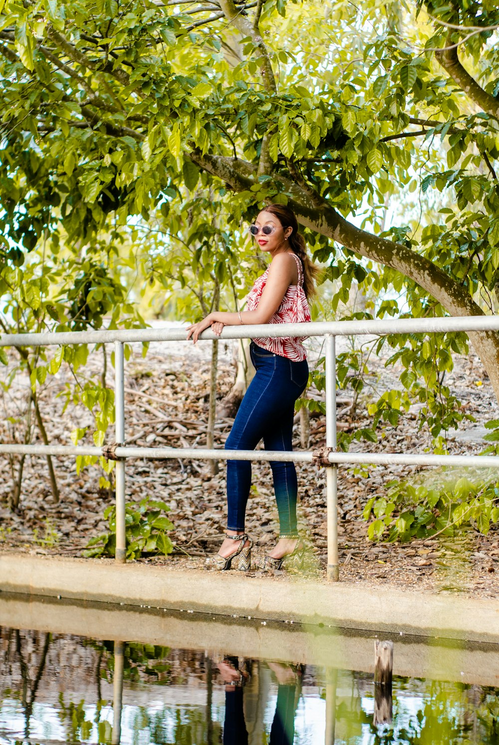 woman in blue denim jeans standing on white metal fence during daytime