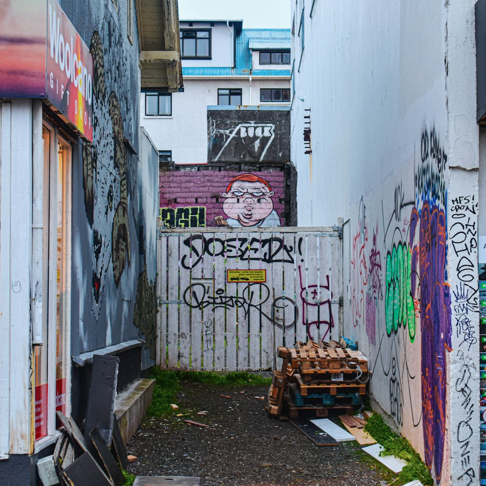 brown wooden bench beside white wall with graffiti