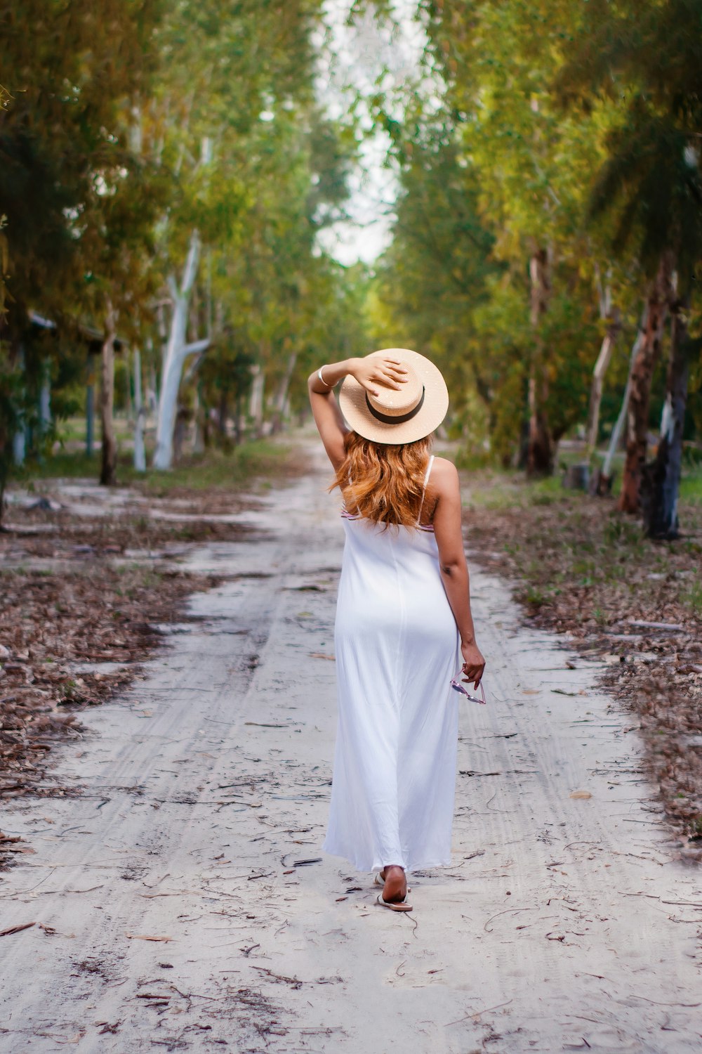 Mujer en vestido blanco caminando por el camino